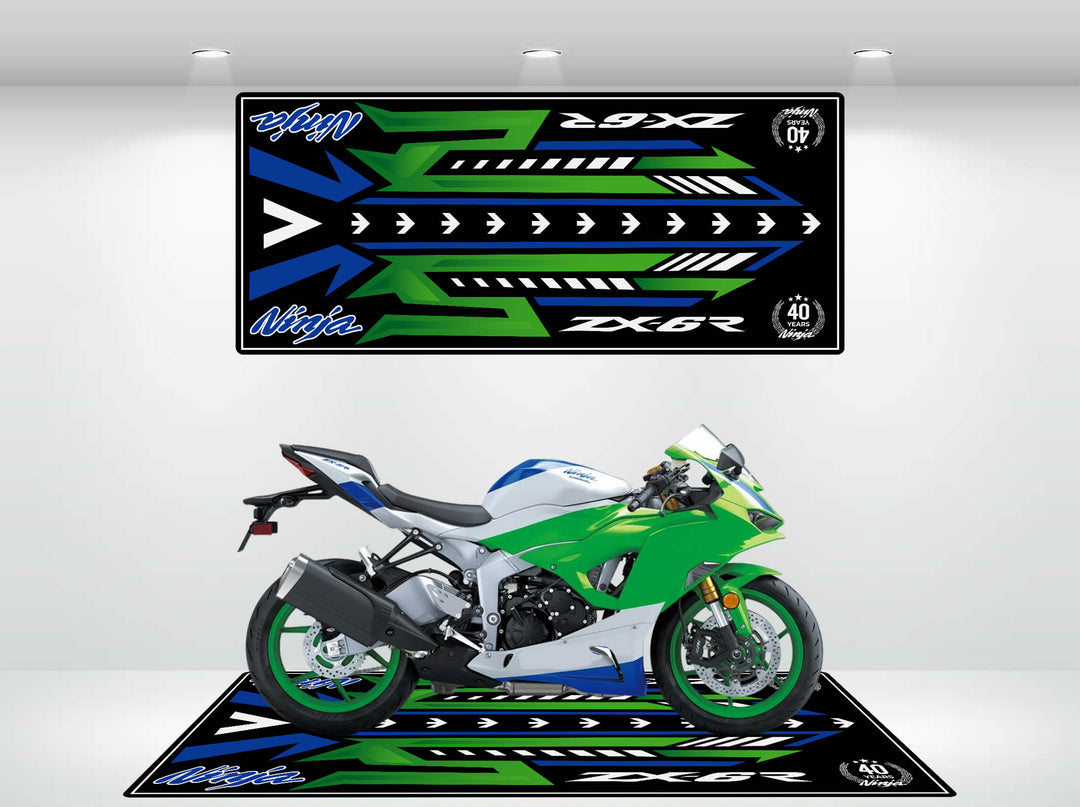 A Ninja ZX-6R 40th Anniversary motorcycle sits on a matching Motorcycle Pit Mat in green, blue, black, and white with stylized text and arrows. Above it hangs a wall banner featuring the same bold design.