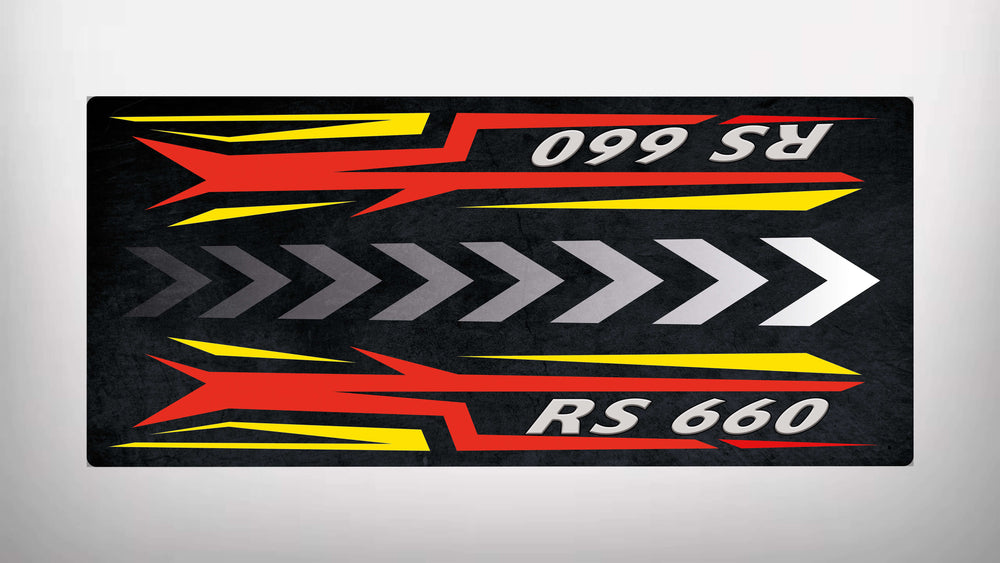 The Motorcycle Pit Mat for RS660 features a bold RS 660 design, with red and yellow angular shapes and gray arrows conveying speed. These elements mirror horizontally against a dark background, enhancing its dynamic look.