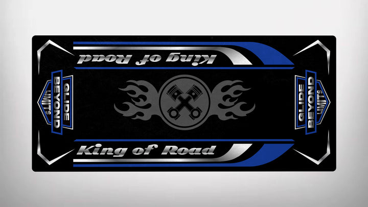 This Motorcycle Pit Mat, Motorcycle Mat for King of Road, features a black and blue design with stylized King of Road text, silver stripes, flaming wrench symbols, and the phrase Glide Beyond Limits. Its sleek, symmetrical design exudes durability with a metallic appearance.