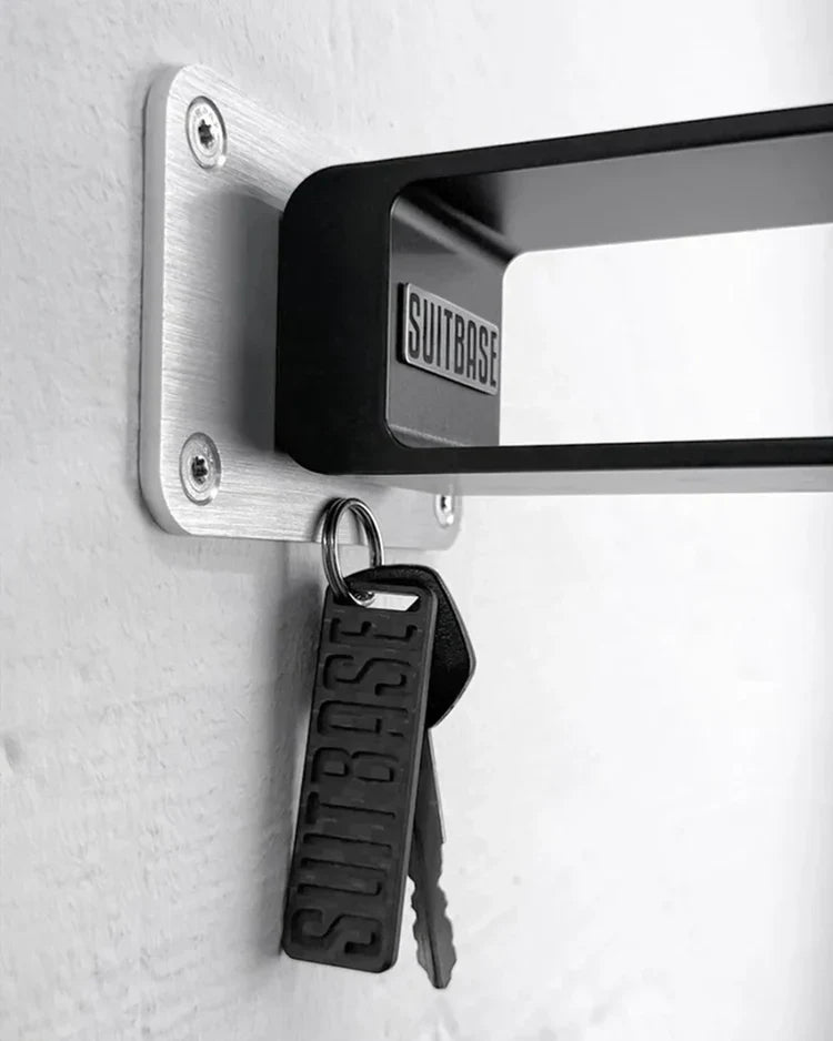 Keychain and keys attached to a wall-mounted aluminum bracket with 'SUITBASE' branding.