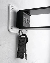 Keychain and keys attached to a wall-mounted aluminum bracket with 'SUITBASE' branding.