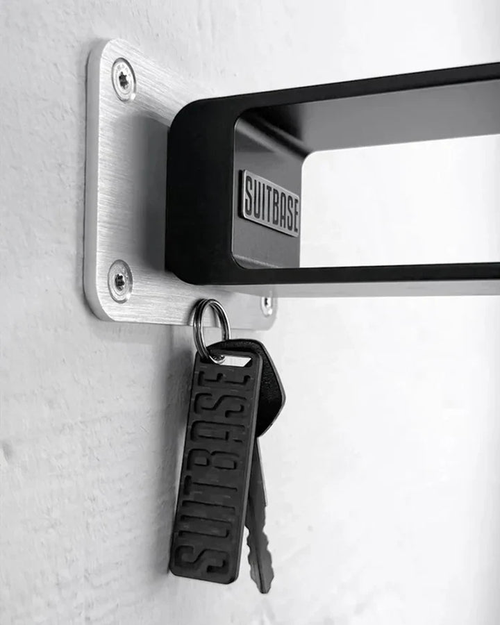 Keychain and keys attached to a wall-mounted aluminum bracket with 'SUITBASE' branding.