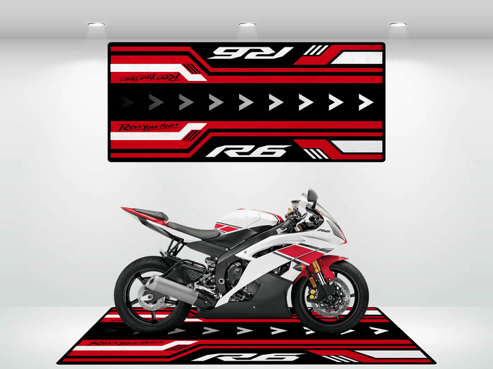 The Motorcycle Pit Mat complements the Yamaha R6 with its white and red theme, featuring coordinating arrows, stripes, and text. The mat enhances the bikes sleek aerodynamic design, visible exhaust, and disc brakes—ideal for a stylish garage floor.